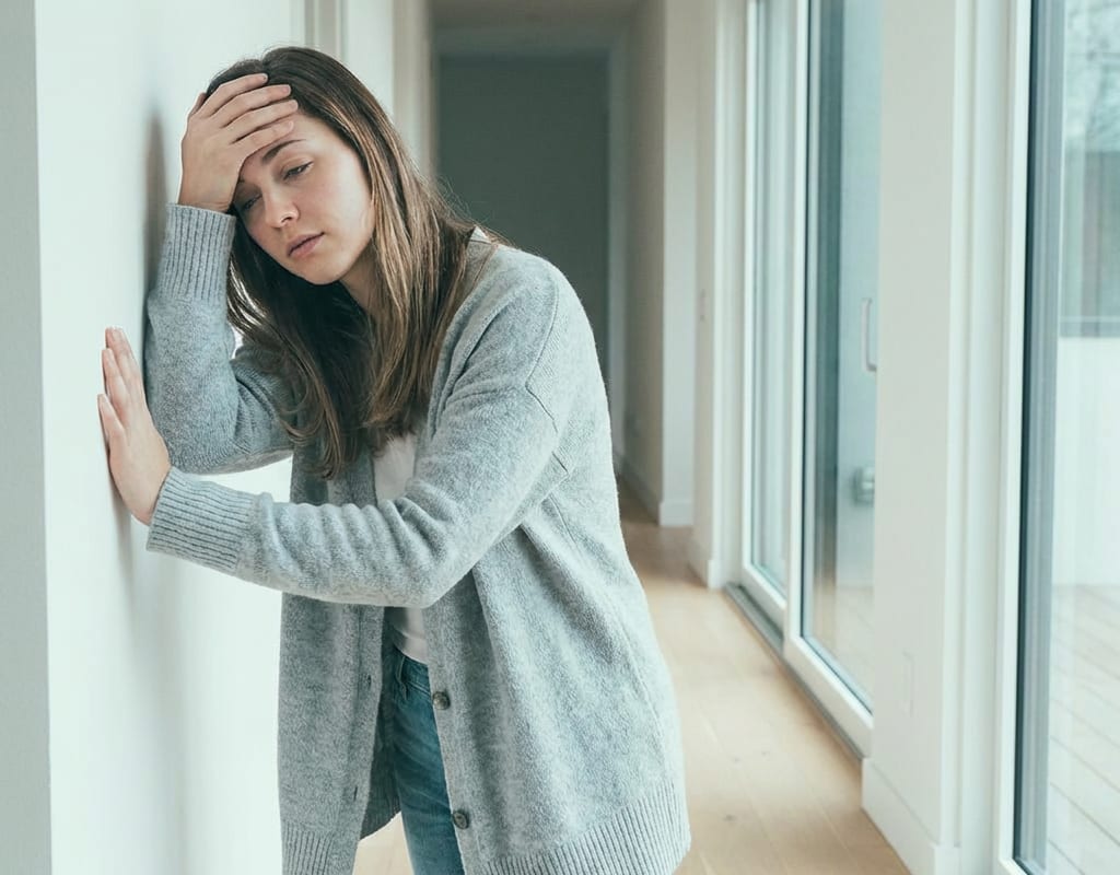 Junge Frau fasst sich an die Stirn wegen Schwindel durch niedrigen Blutdruck